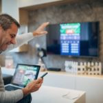 Man holding tablet sitting in front of TV