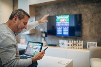 Man holding tablet sitting in front of TV