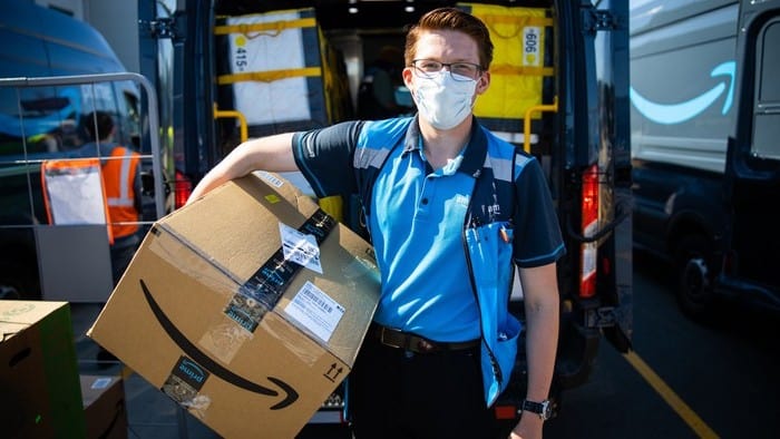 amazon.com stock represented by man holding parcel printed with amazon logo