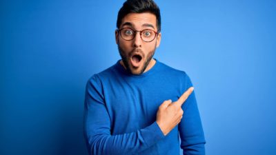 A young man pointing up looking amazed, indicating a surging share price movement for an ASX company