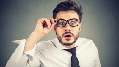 A businessman holds his glasses in concern, indicating uncertainly in the ASX share price