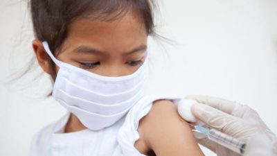 covid vaccine stocks represented by little girl receiving vaccine needle