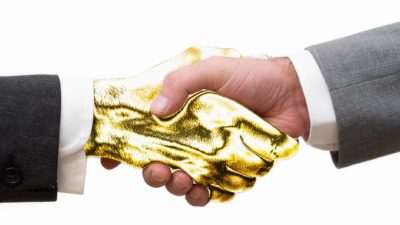 Two hands grasp together, one painted gold, representing a golden handshake or deal between two ASX share companies
