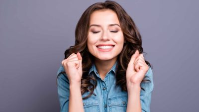 A young woman smiling and looking happy, indicating a positive share price movement on the ASX market