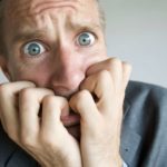A worried man chews his fingers, indicating a share price crash or drop on the ASX 200