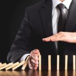 asx share price in trading halt represented by business man stopping falling row of dominoes