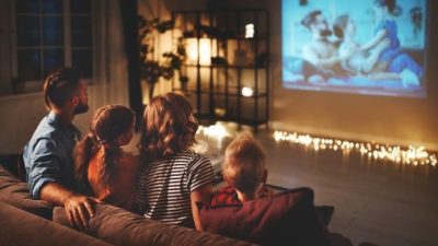 Family on couch watches movie projection