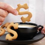 Man with cookie dollar signs and a cup of coffee.