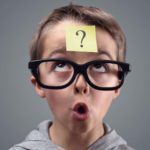 A boy with a question mark on a sticky note on his forehead looking up as if watching an ASX share price.