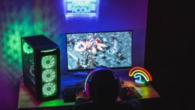 A young boy in a darkened room plays on his gaming console