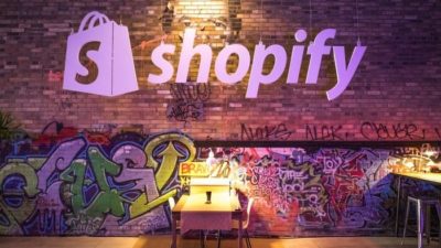 shopify stock represented by shopify logo on wall of lane way