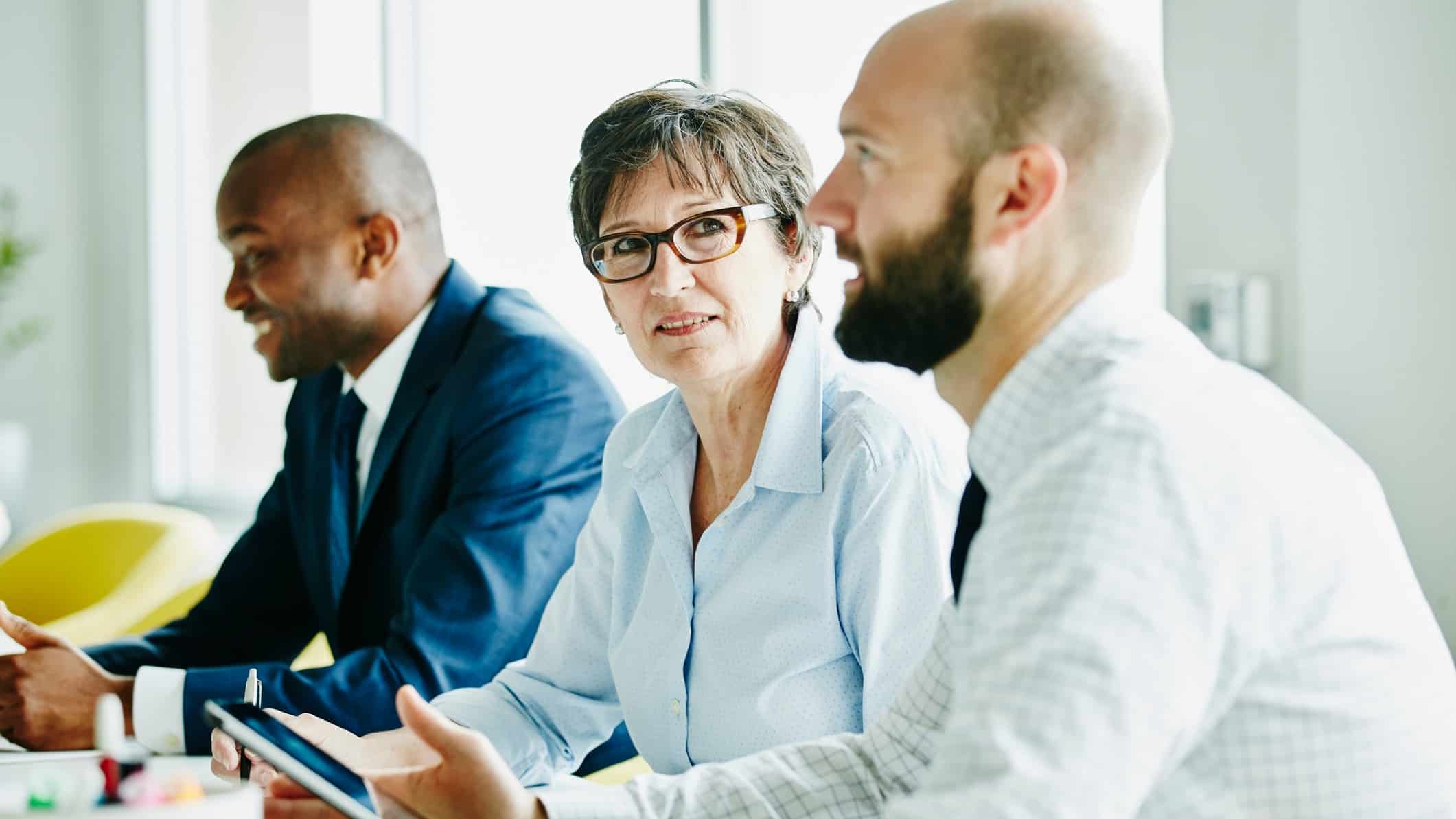 Three board members sit at a table waiting for the ANZ AGM to start