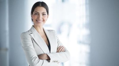 Young female investor in business attire smiling with folded arms