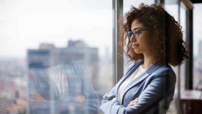 Young Female investor gazes out window at cityscape