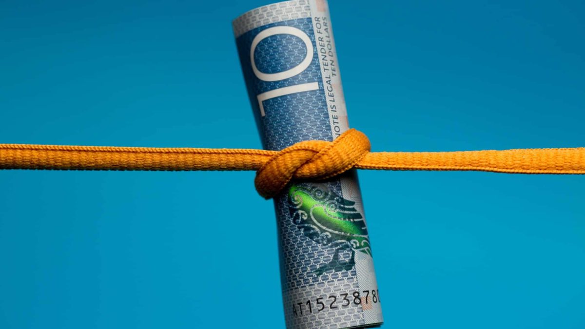 New Zealand $10 note being squeezed by an orange string to show recession