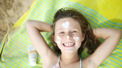 Smiling girl with sunscreen on face 16.9
