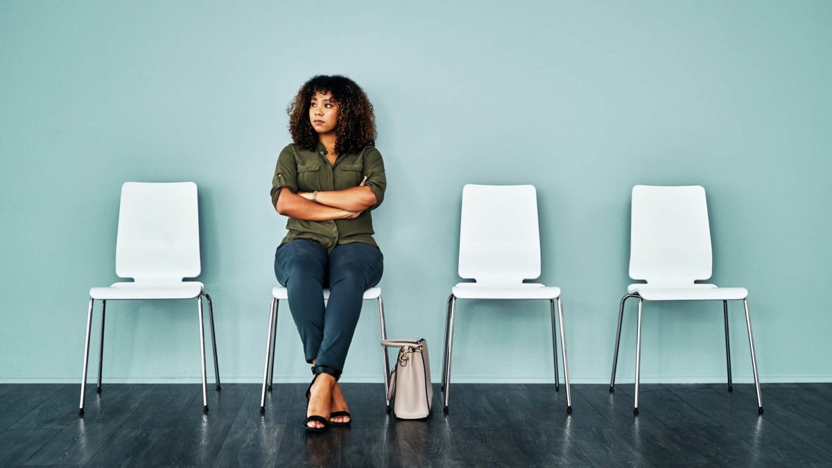 Worried unemployed woman sits on white chair waiting for job interview