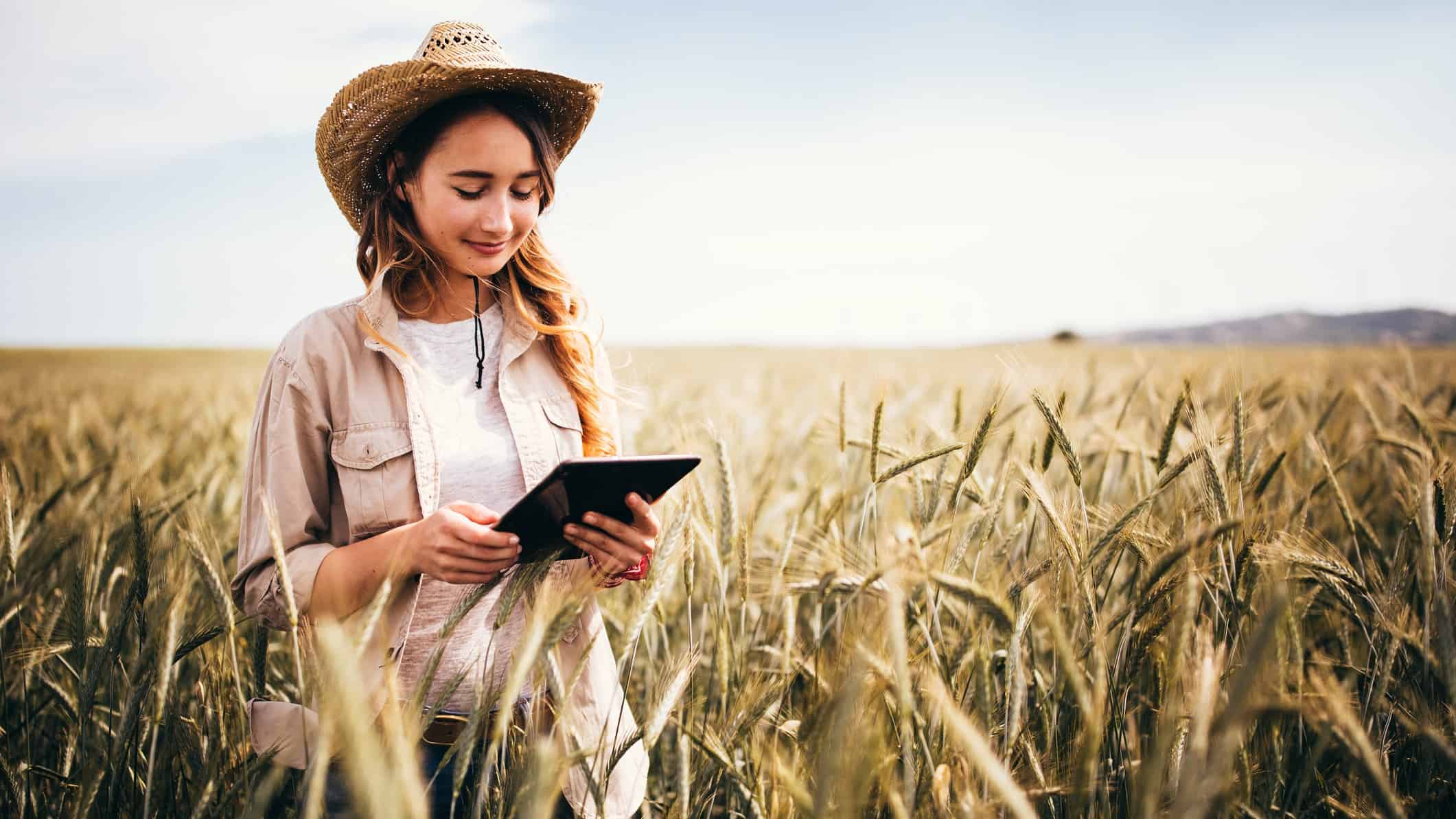 Agricultural ASX share price on watch represented by farmer in field looking at tablet computer.
