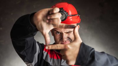 Mining worker making frame with his hands and peering through it