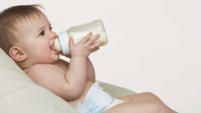A happy baby drinking milk from a bottle