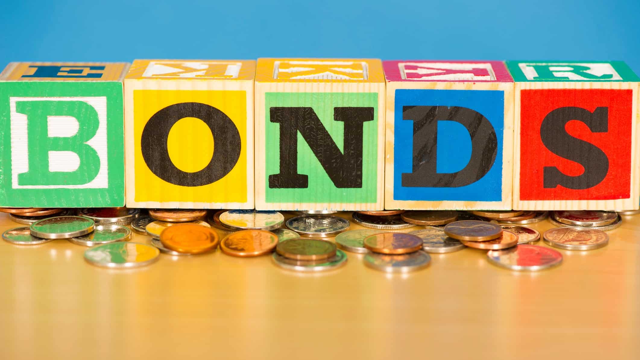 bond yields represented by wooden blocks spelling bonds atop coins