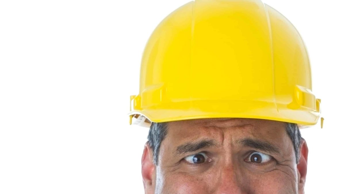 Man in hard hat rolling his eyes at a falling ASX share price. builder