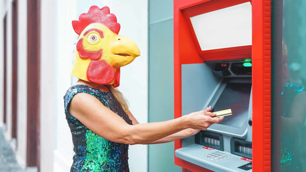 Woman wearing chicken mask drawing money out at ATM