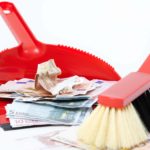 Broom sweeping cash into dust pan.