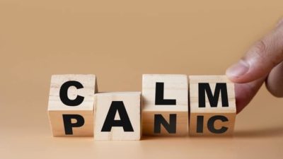falling nasdaq and asx share price represented by wooden blocks spelling calm and panic