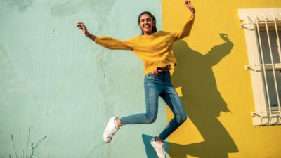 rising asx share price represented by woman jumping in the air happily