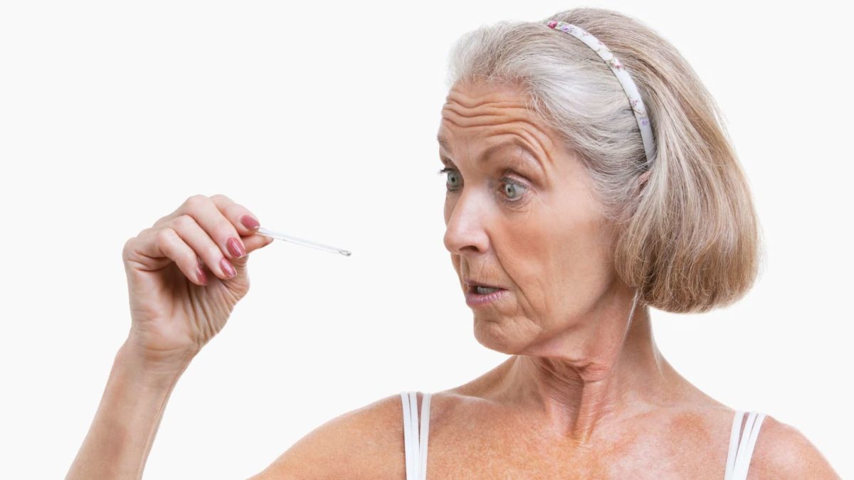A woman looks surprised as she checks an old-fashion thermometer, indicating a change in share price moevement for biotech companies