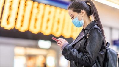 women loking at her phone while wearing a mask