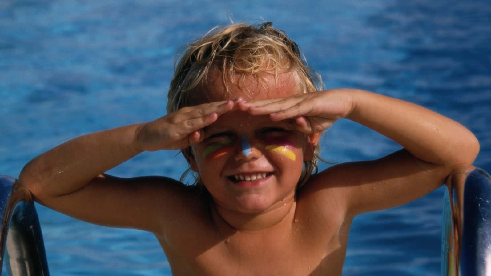 A young boy wearing zinc sunscreen in a swimming pool