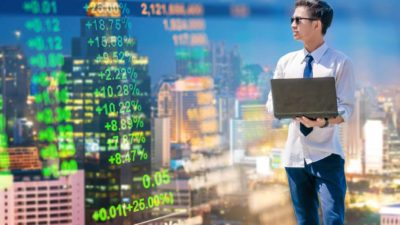 Young man with laptop watching stocks and trends while thinking