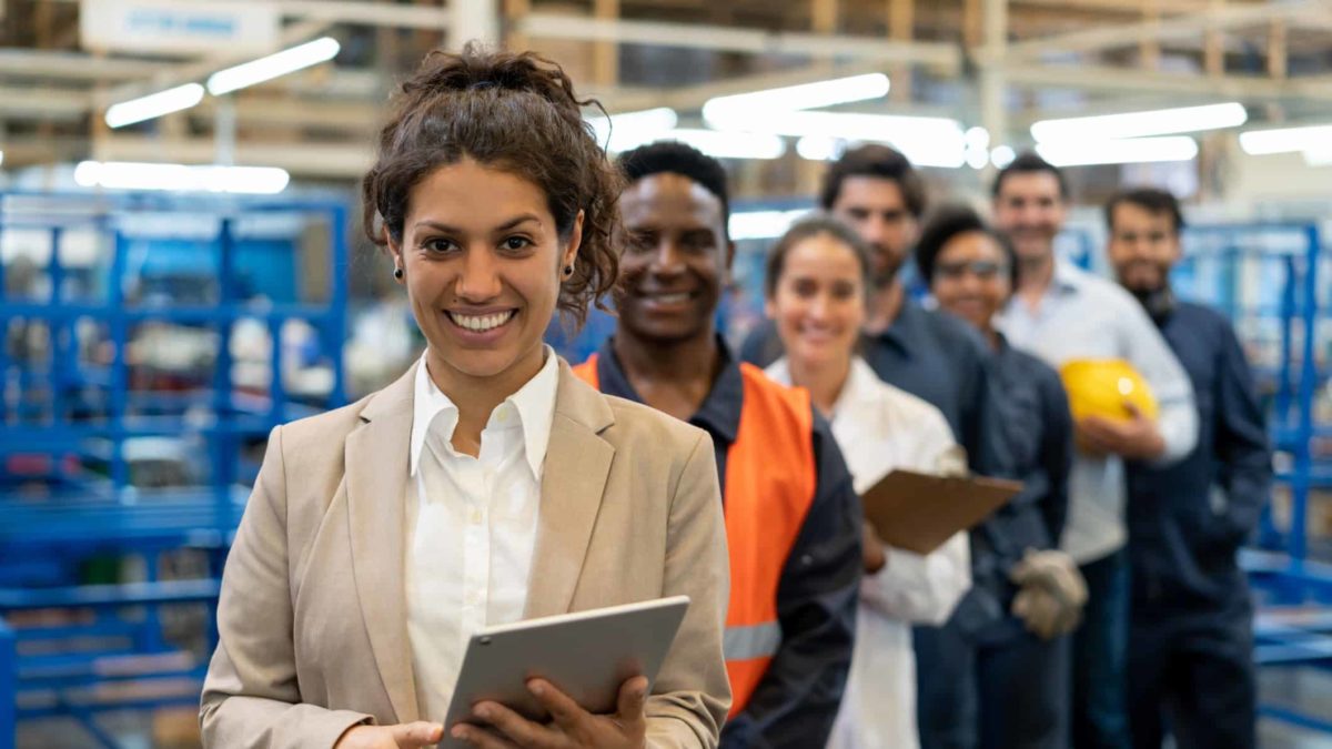 line of workers in a manufacturing factory with tablets in their hands