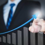 A businessman points to an arrow going up on a graph, indicating a share price rise for an ASX company.