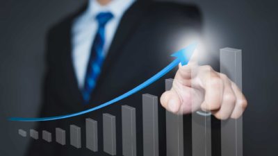 A businessman points to and arrow going up on a graph, indicating a share price rise for an ASX company