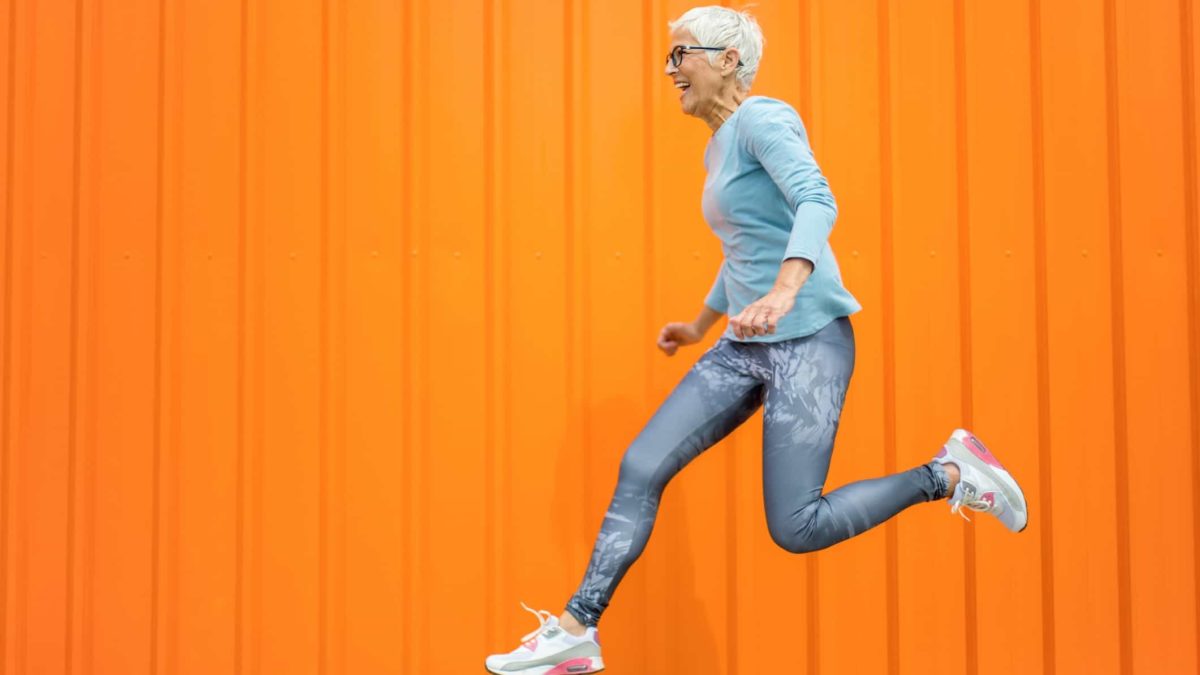 rising asx share price represented by senior lady jumping against orange background
