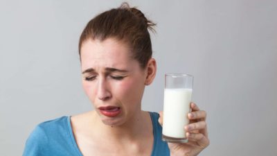 falling milk asx share price represented by frowning woman tasting sour milk