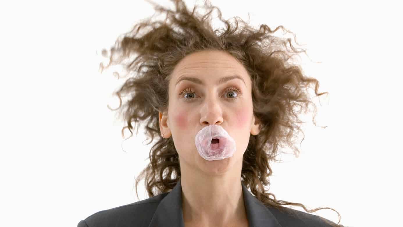 A woman bursts her bubblegum, indicating a sinking share price