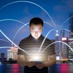 A man is connected via his laptop or smart phone using cloud tech, indicating share price movement for ASX tech shares and asx tech shares