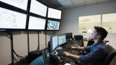 man working on and monitoring cyber security in a room full of computers