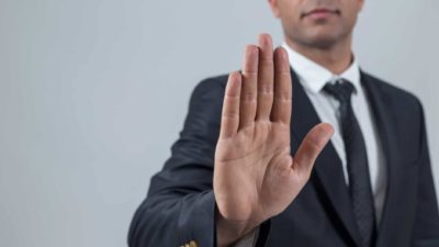 An ASX share investor holds his hand out in a stop sign