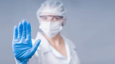 health worker wearing personal protective equipment and gesturing stop with her hands