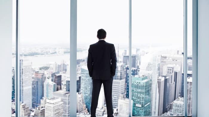 man looking through window at sky scraper buildings