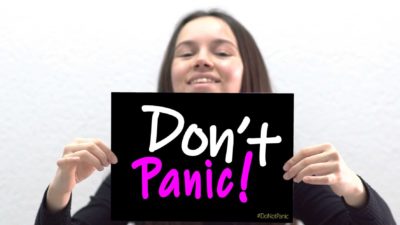 A smiling woman holds a sign saying 'Don't panic', indicating unwanted share price movement