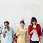 people lined up and using smart phones and laptops