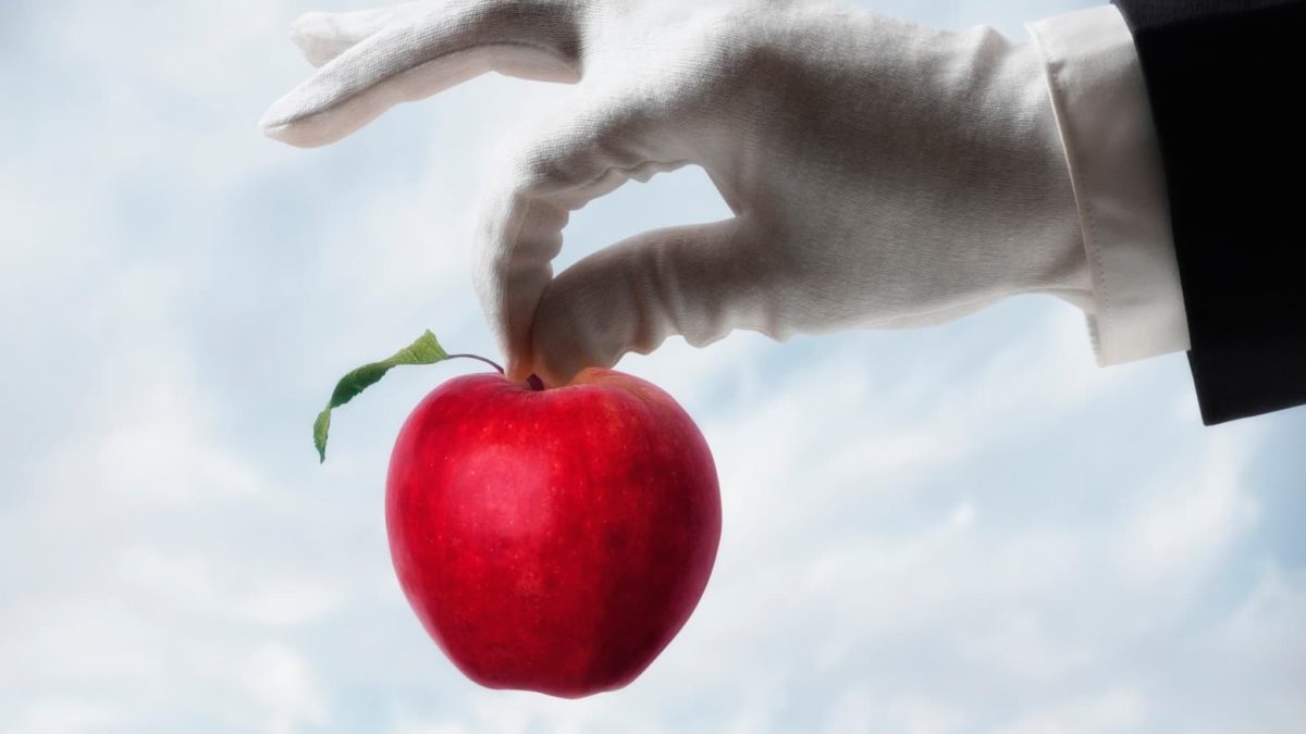 A gloved hand picks up a bright red apple, indicating ASX share prices that may be ripe for the picking