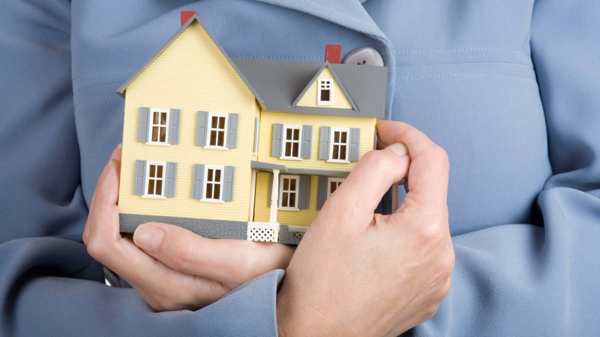 property prices represented by person holding on to miniature house