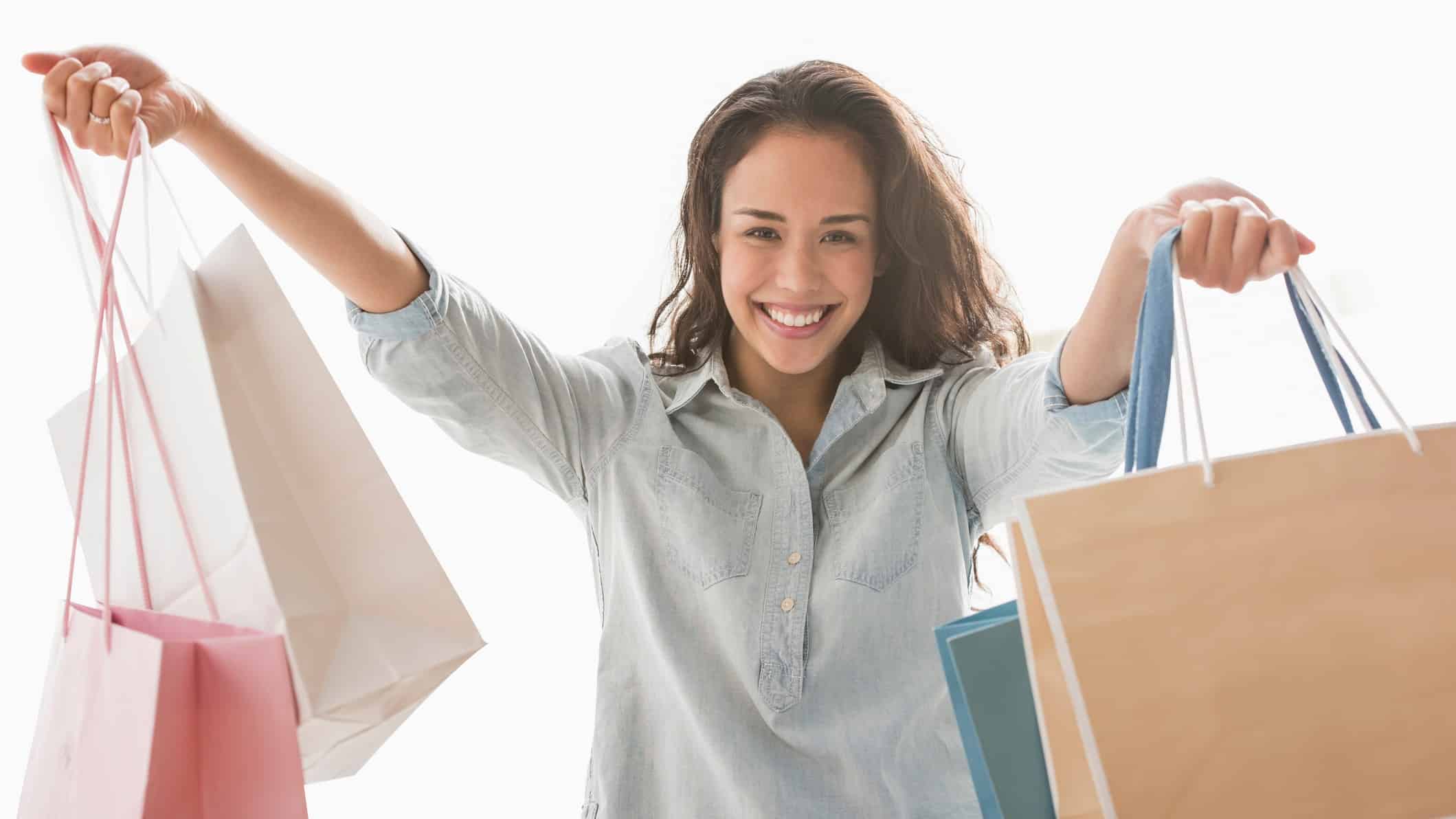 A happy shopper lifts her bags high, indicating a rising share price in ASX retail companies